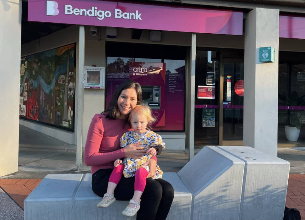 Tanya Hall and baby Isabelle in front the the Community Bank Samford